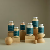 Numerous glass jars containing our luxury bath salts displayed atop oak wooden blocks of various sizes and shapes.