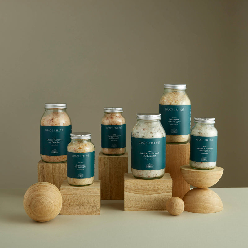 Numerous glass jars containing our luxury bath salts displayed atop oak wooden blocks of various sizes and shapes.